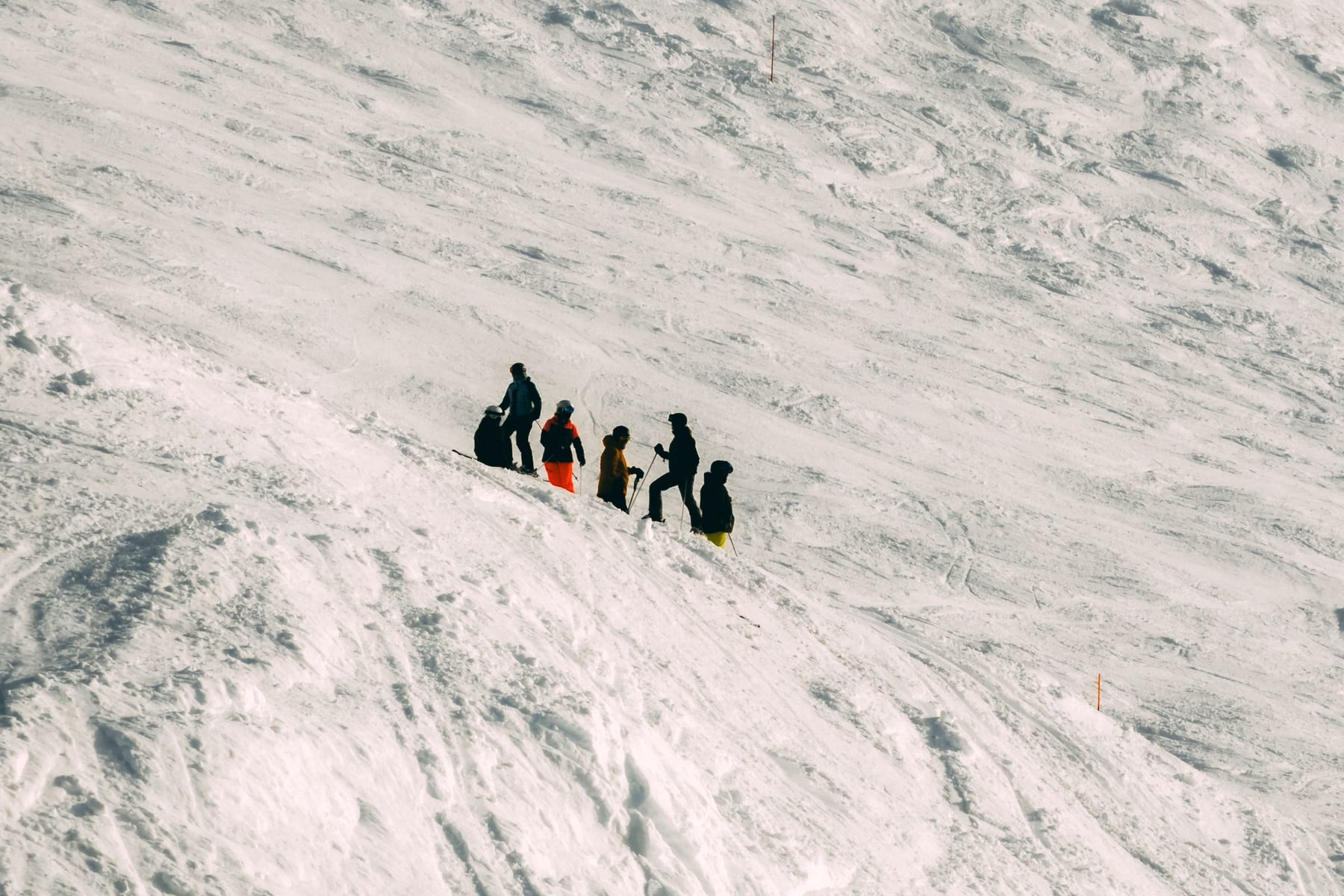 Een skileraar geeft les aan een groep op een besneeuwde piste, van een afstand gefotografeerd